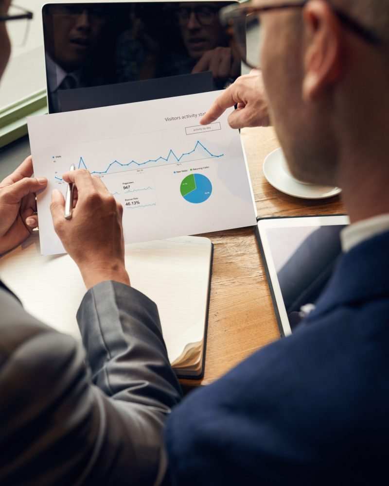 Business people analyzing visitors activity statistics, view over the shoulder